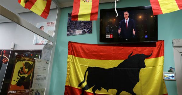 Foto: Banderas españolas al lado de una pantalla de televisión con la imagen de Pedro Sánchez en el debate. (Reuters)