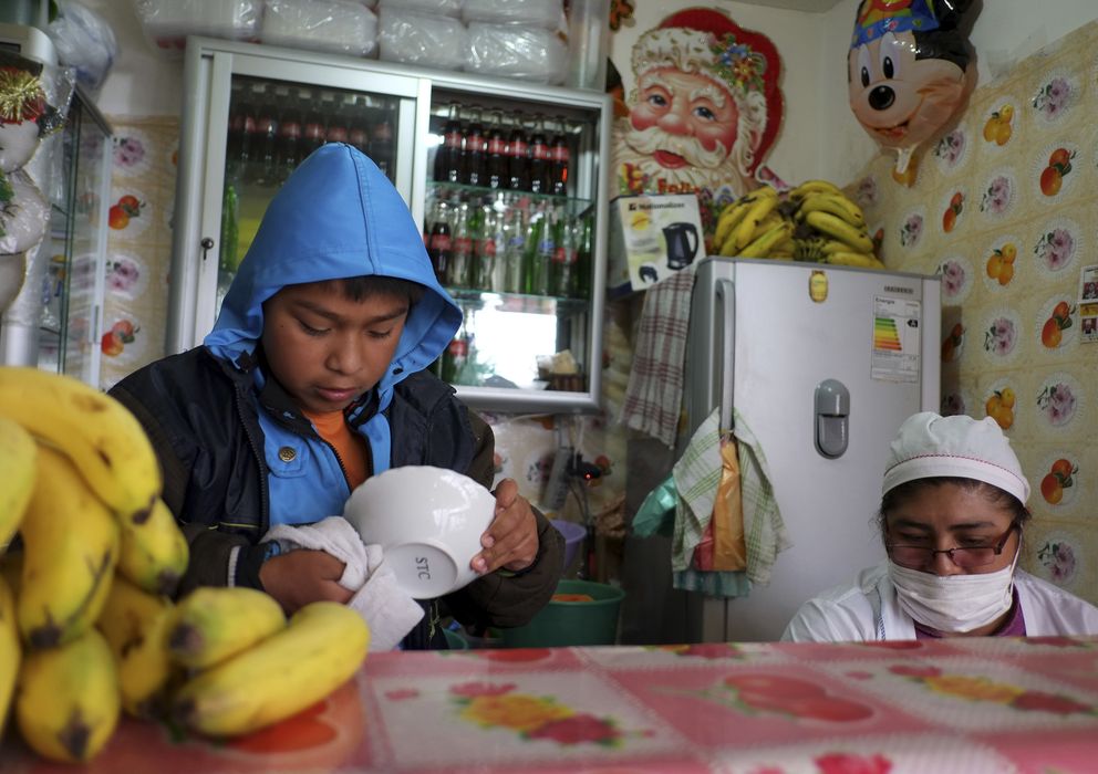 Foto: Un niño seca un bol en el puesto de comida donde trabaja en La Paz. (Reuters)