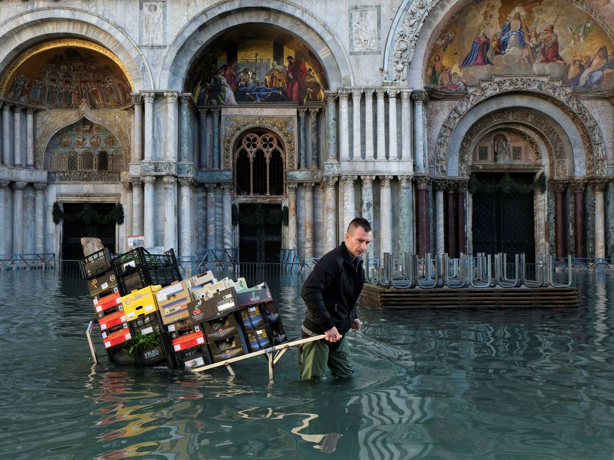 Foto: Un hombre cargando con fruta y verdura en las pasadas inundaciones en Venecia el pasado diciembre. (Reuters)