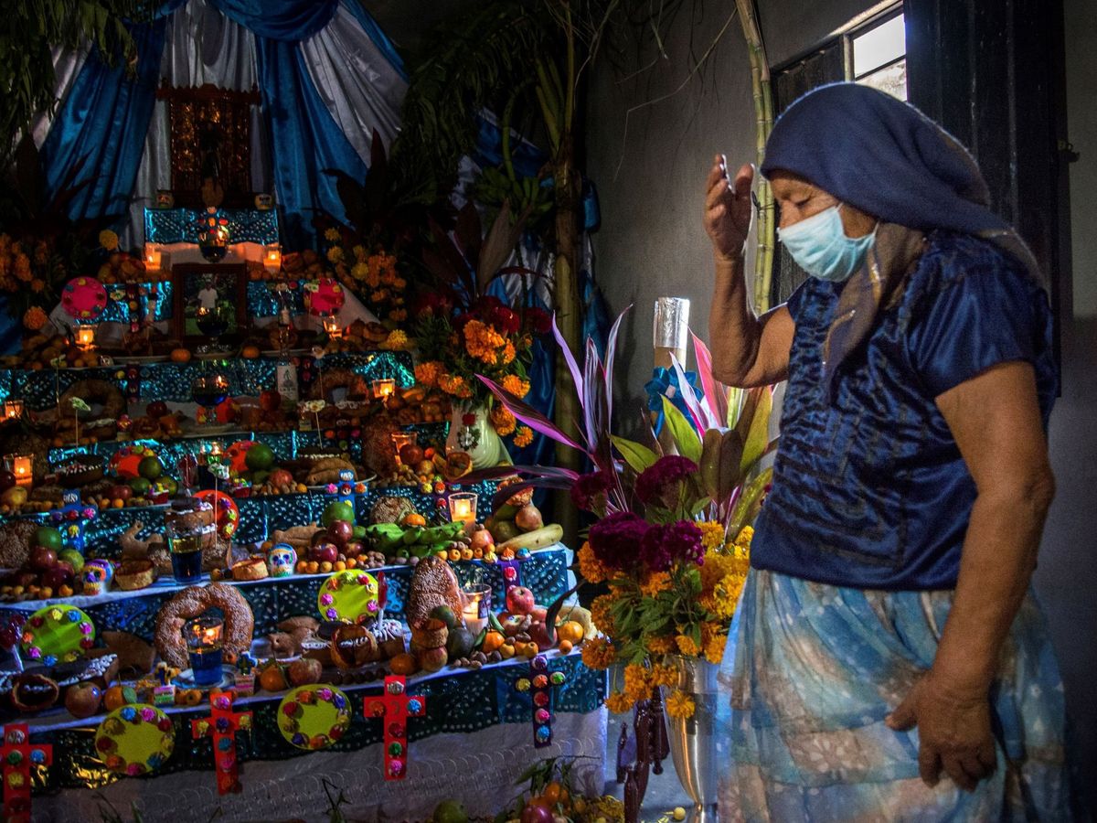 Foto: Una mujer reza frente a su altar de Día de Muertos. (EFE)
