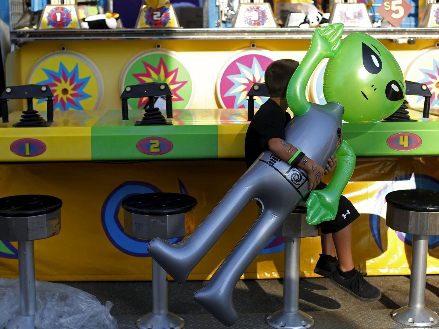 A boy carries an inflatable alien toy prize while sitting on a stool at the Iowa State Fair in Des Moines, Iowa, United States, August 15, 2015.  REUTERS/Jim Young