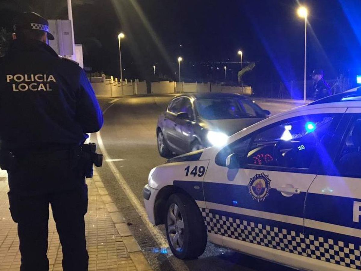 Foto: Un agente junto a un coche de policía en Alicante. (Policía Local de Elche)
