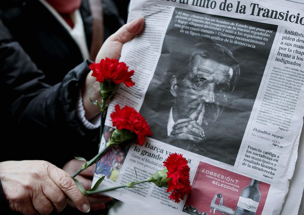 Foto: Una persona sostiene tres claveles ante un portada de un periódico con la imagen de Alfonso Suárez. (EFE)