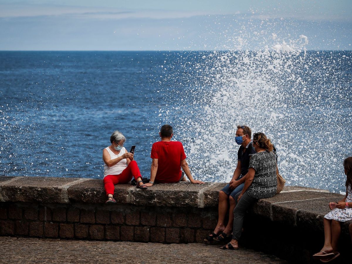 Foto: Varias personas tratan de refrescarse en el paseo de Chillida de San Sebastián. (EFE)