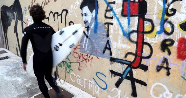 Foto: Un surfista pasa junto a una pintada a favor de la banda terrorista ETA en el barrio de Gros de San Sebastián. (EFE)