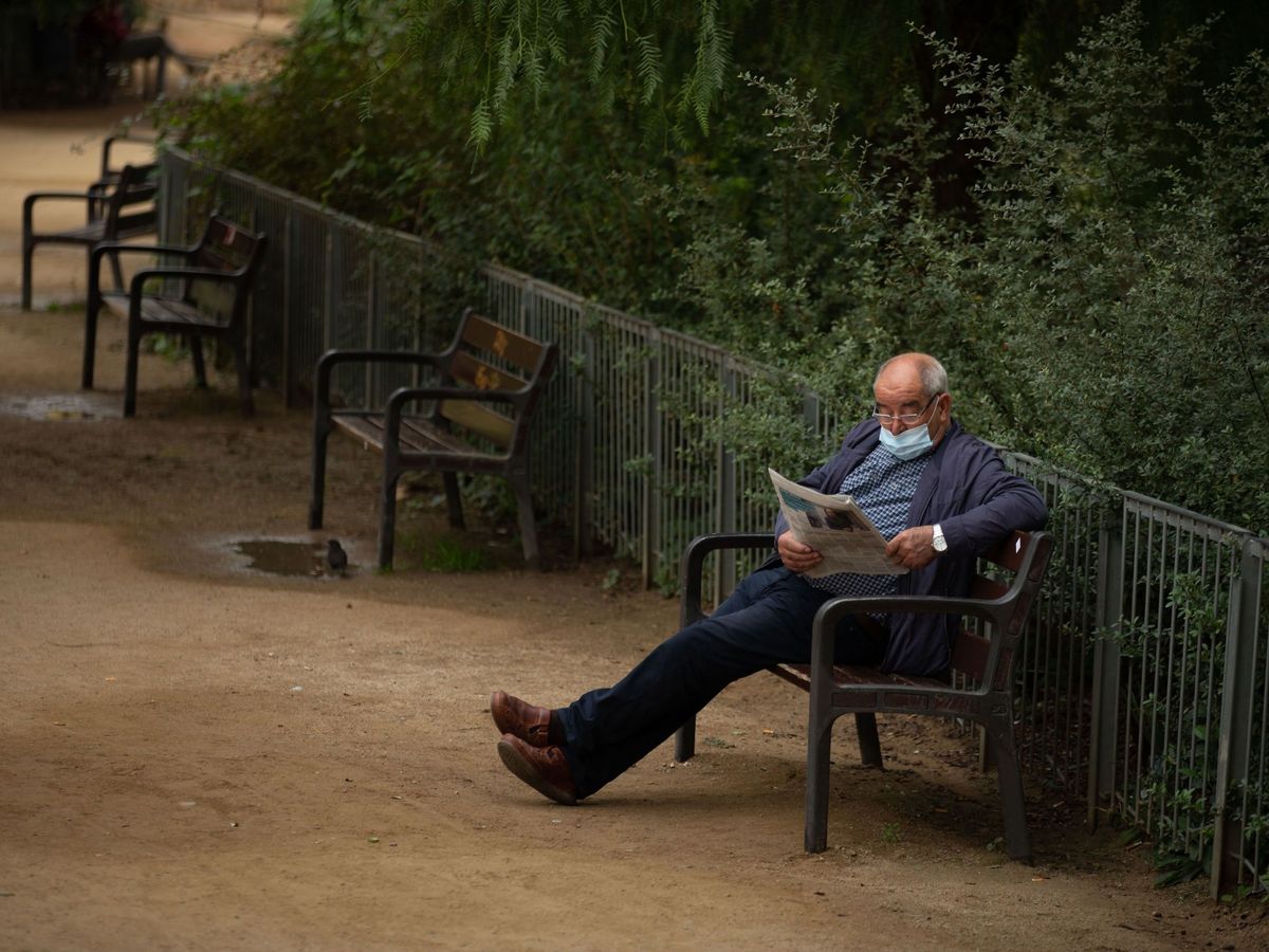 Foto: Un hombre lee el periódico en las inmediaciones de la Sagrada Familia. (EFE/Enric Fontcuberta)