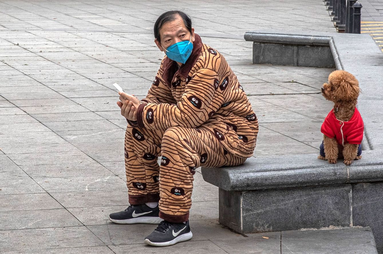 Un hombre protegido con una mascarilla descansa de un paseo con su perro en Wuhan (China), este lunes. (EFE)