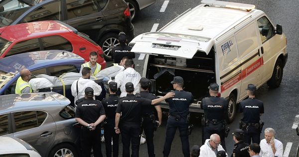 Foto: Funcionarios judiciales trasladan el cuerpo sin vida de una de las dos personas fallecidas esta mañana en la calle Sueca, donde un policía ha muerto acuchillado. (EFE)
