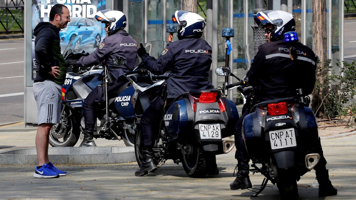 Unos policías informan a un viandante en el Paseo del Prado, en Madrid de que debe volver a casa. (EFE)