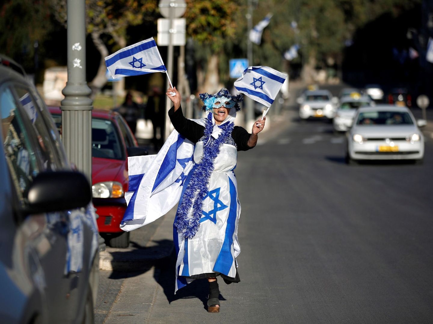 Una mujer cubierta de banderas israelíes baila por las calles de Jerusalén. EFE
