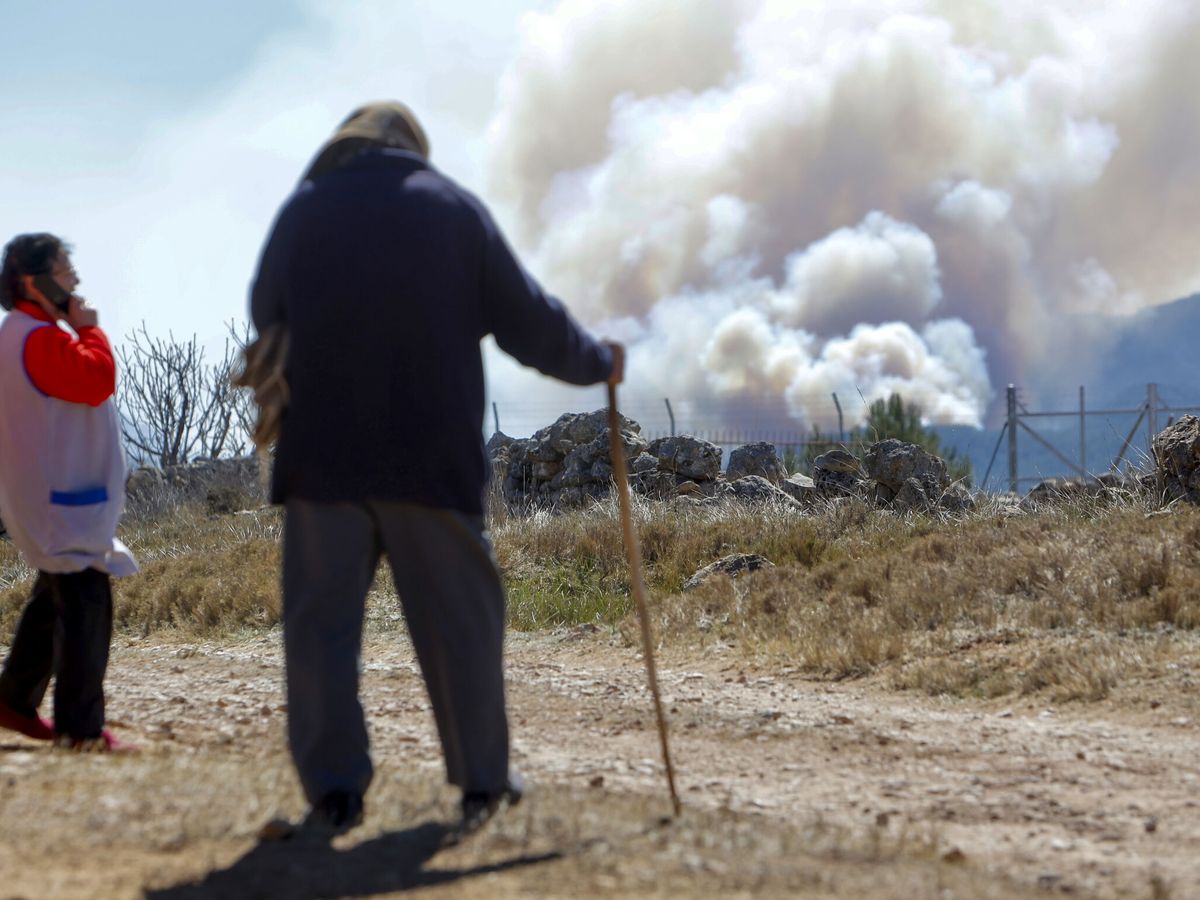 Foto: Dos vecinos observan el humo generado por el incendio de Villanuena de Viver, Castellón. (EFE/Domenech Castelló)