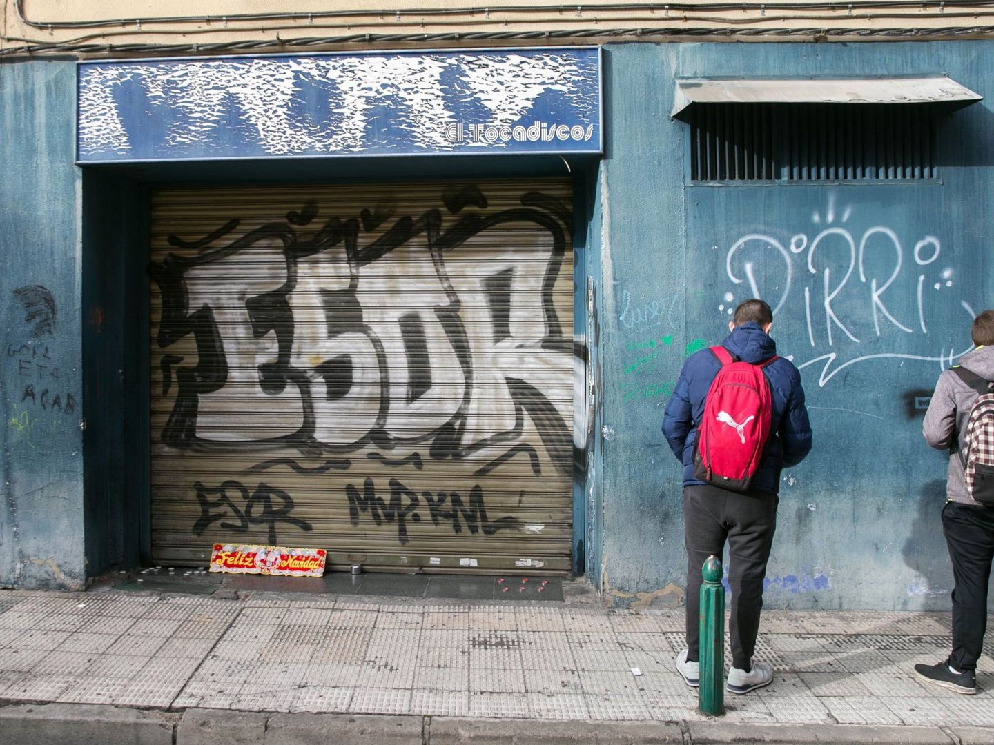 Unos jóvenes miran la puerta del bar a cuyas puertas murió Víctor Laínez. (EFE)
