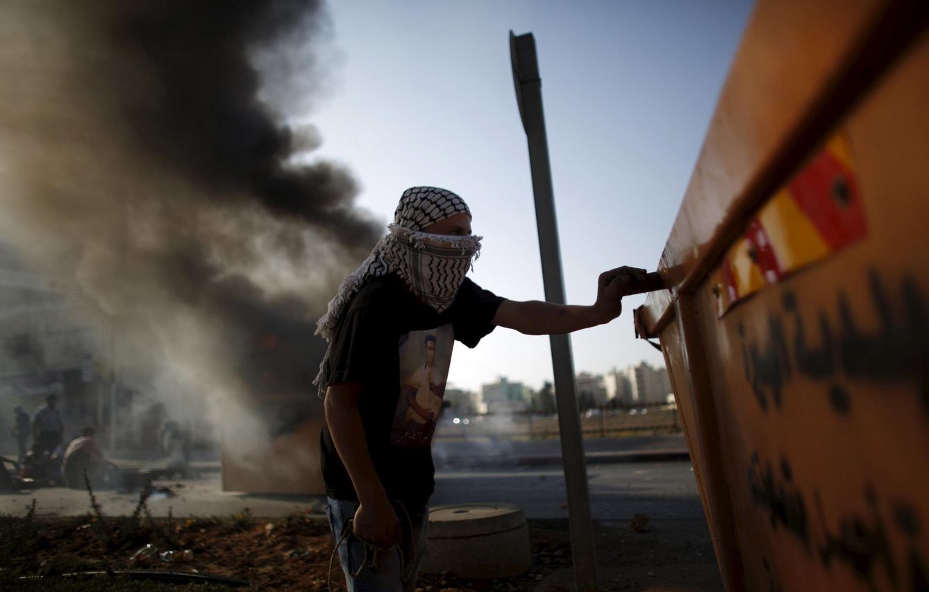 Un manifestante palestino se protege tras un contenedor durante choques con fuerzas israelíes en Ramala, Cisjordania. (Reuters)