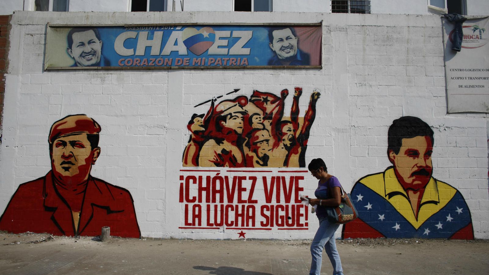 Foto: Una mujer pasa frente a un mural de los presidentes Hugo Chávez y Nicolás Maduro (Reuters)
