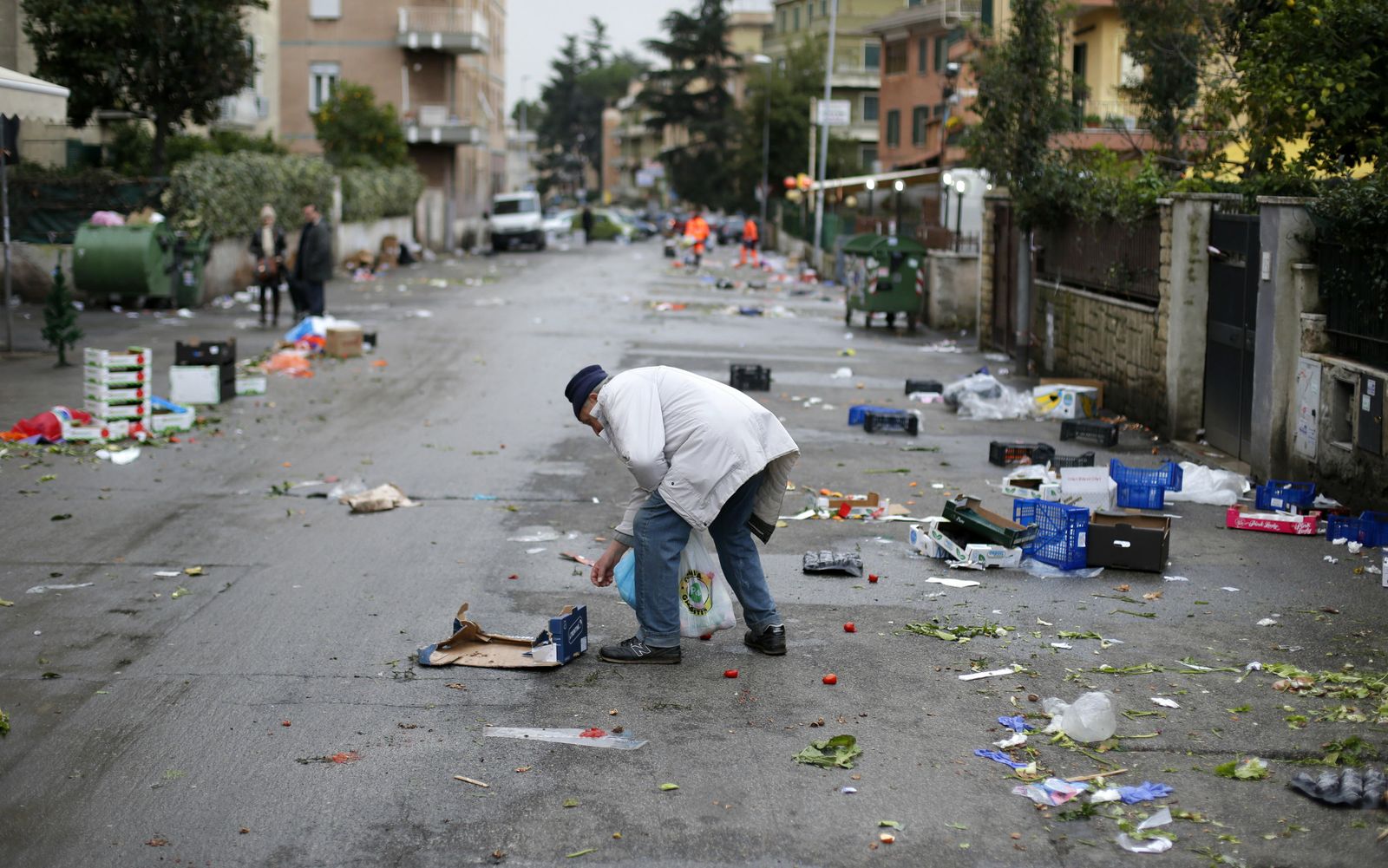 Foto: Un hombre recoge comida abandonada en el suelo tras celebrarse un mercado callejero en una calle de Roma. (Reuters)