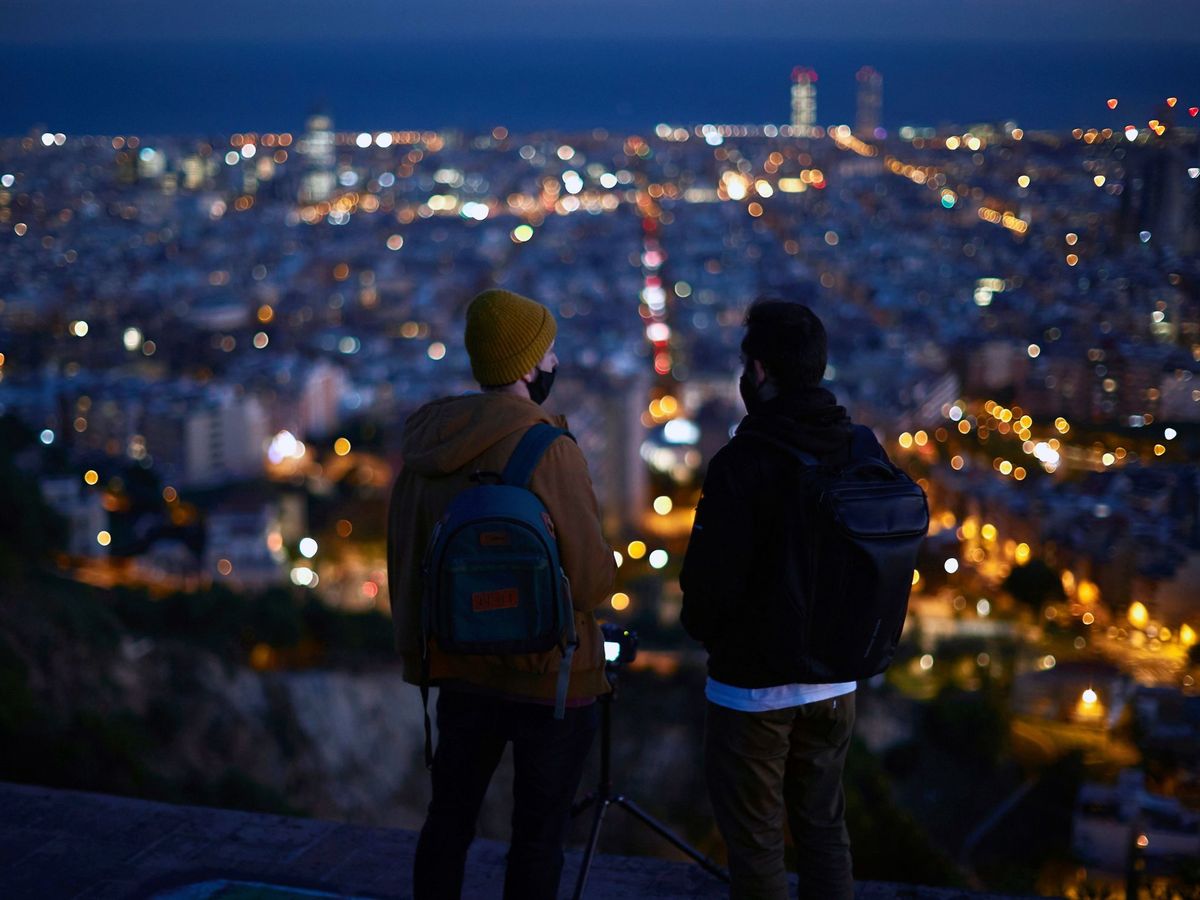 Foto: Dos personas observan el atardecer desde un mirador en Barcelona (EFE)