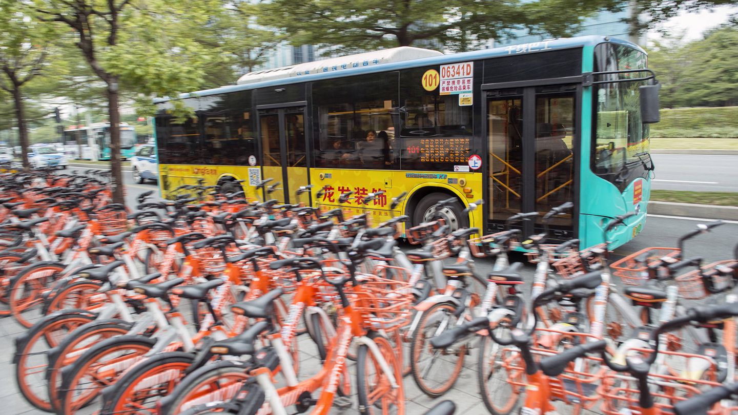 Un autobús eléctrico pasa frente a un aparcamiento de bicicletas compartidas, otro avance en la movilidad de Shenzhen. (Z. Aldama)