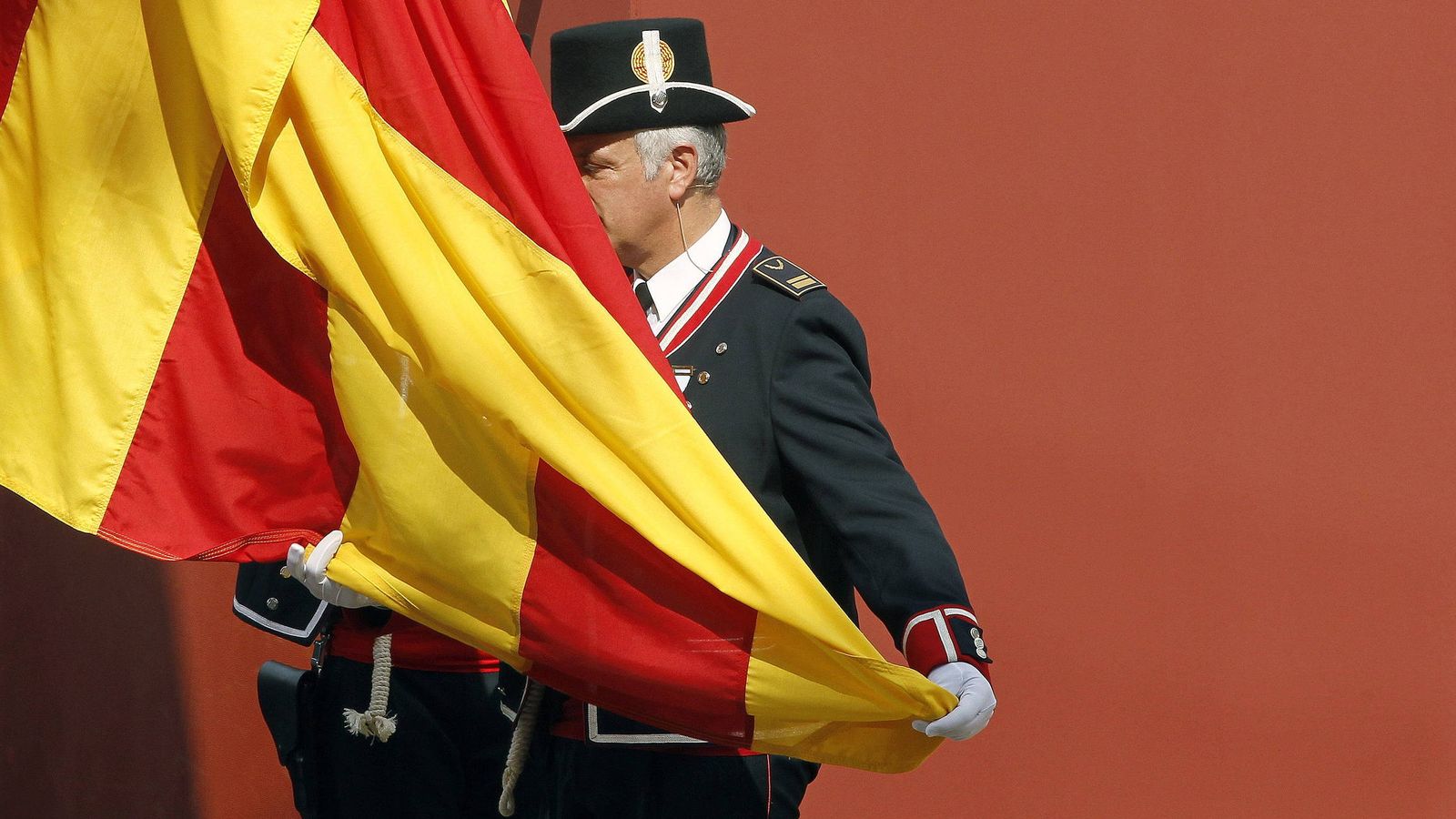 Foto: Un miembro del cuerpo de policía autonómica iza la bandera catalana. (EFE)