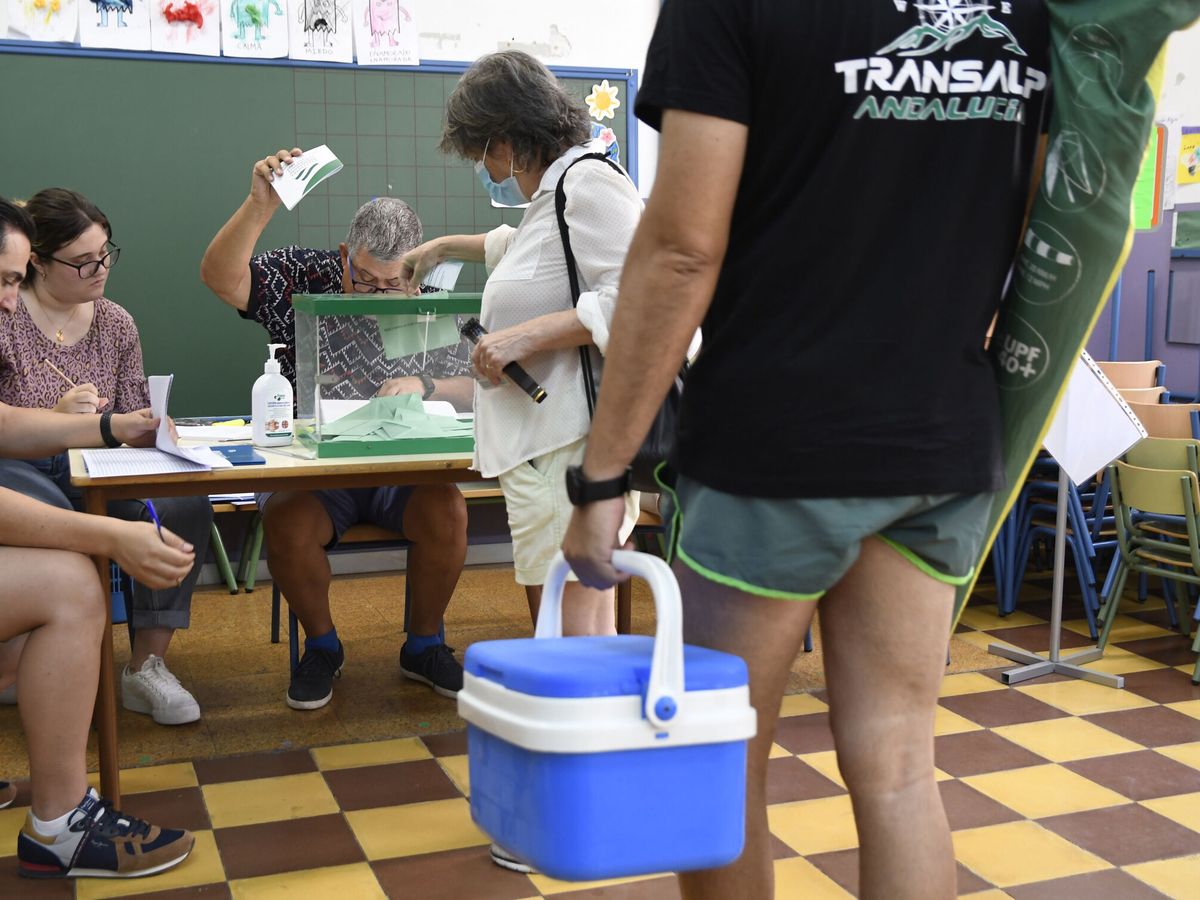 Foto: Un hombre espera para votar con una nevera y una sombrilla, durante las elecciones de junio en Andalucía. (EFE/Carlos Barba)