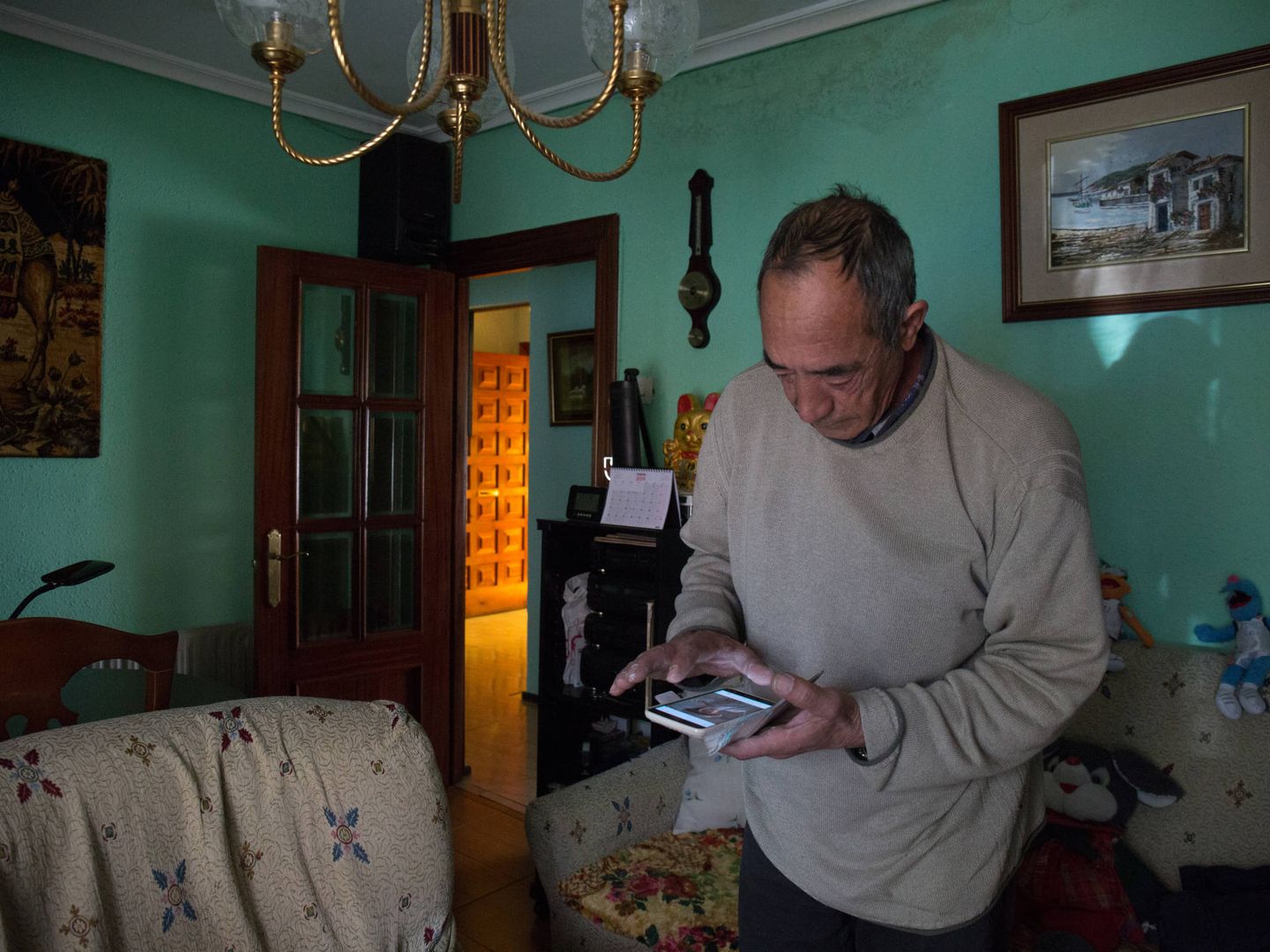 Marcelino observa fotografías de sus hijos en el salón de su vivienda. (D.B.)