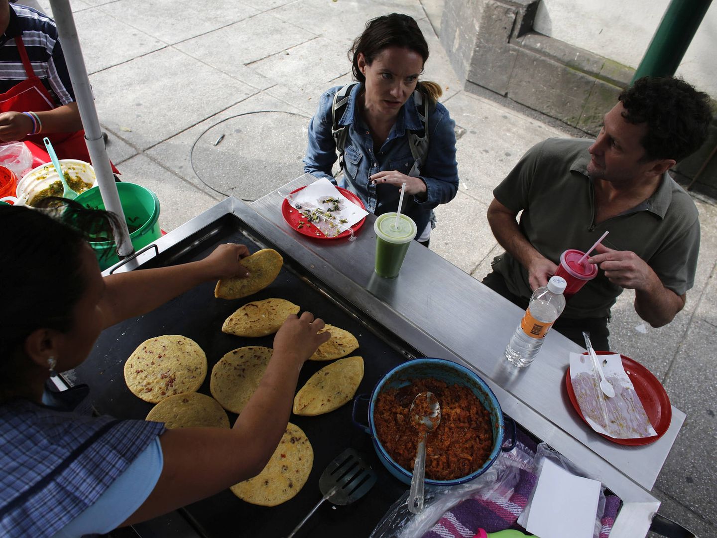 Dos turistas comen tlacoyos en un puesto en Ciudad de México, en octubre de 2013. Muchos platos tradicionales mexicanos, como los nachos con queso, usan 'manchego'. (Reuters)