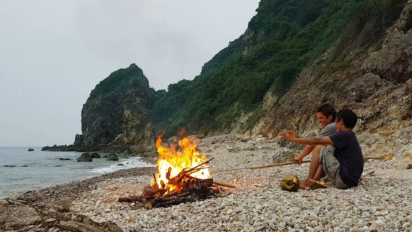 Cerezo y Lang sentados frente al fuego en la isla desierta. (Álvaro Cerezo)