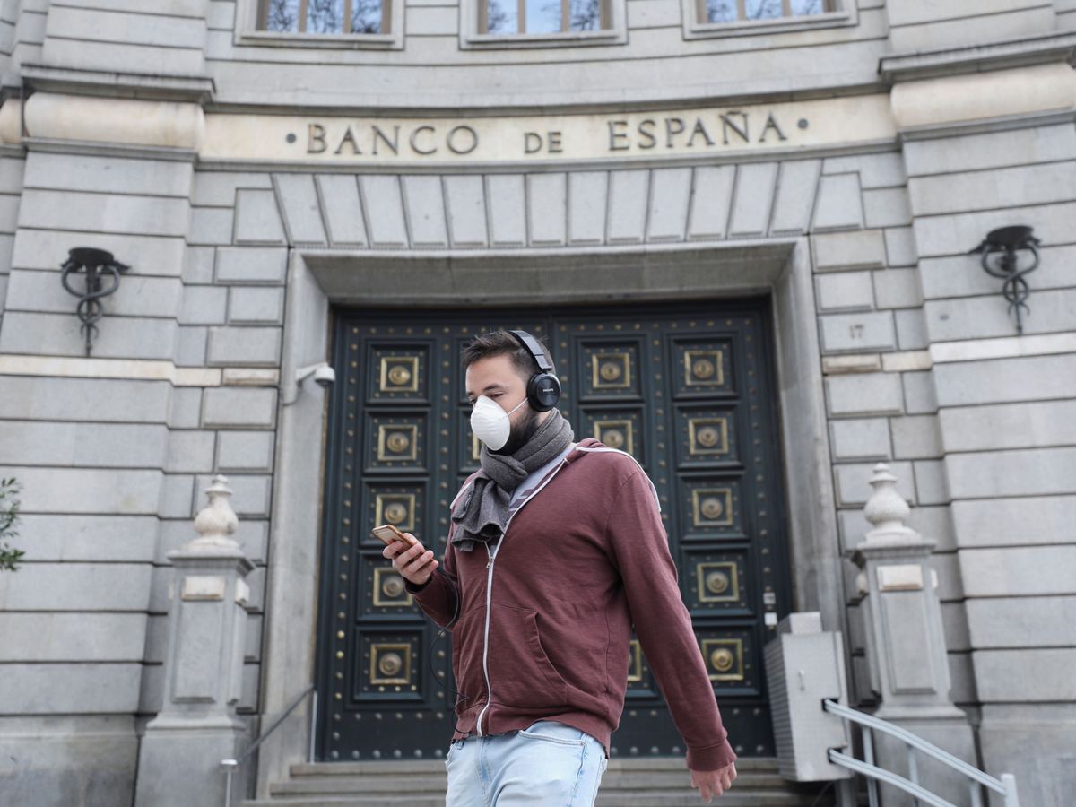 Foto: Una persona lleva una mascarillas de protección delante del Banco de España. (EFE)