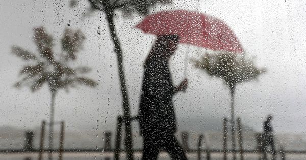 Foto: Una mujer camina bajo la lluvia en el paseo de la Concha de San Sebastián. (EFE) 