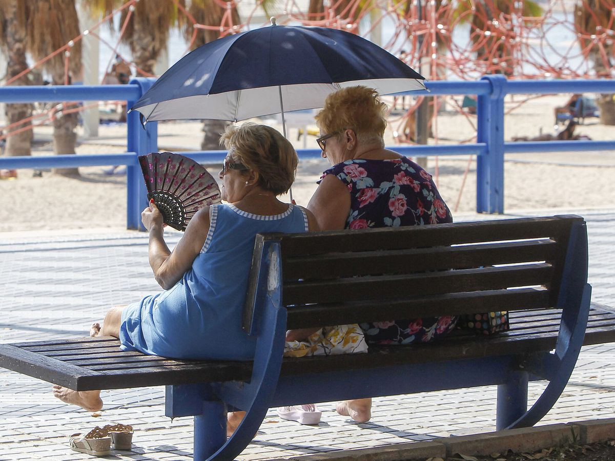 Foto: Dos mujeres se protegen del sol y del calor con abanico y parasol ( EFE/Morell) 