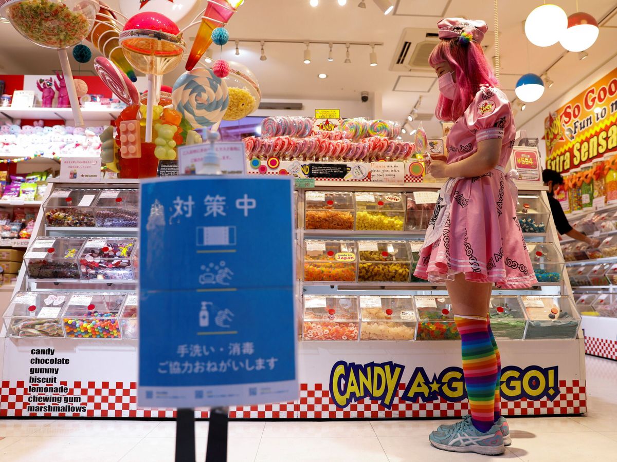 Foto: La empleada de una tienda de dulces trabaja frente a un cartel de medidas de prevención contra el covid-19. (Reuters)