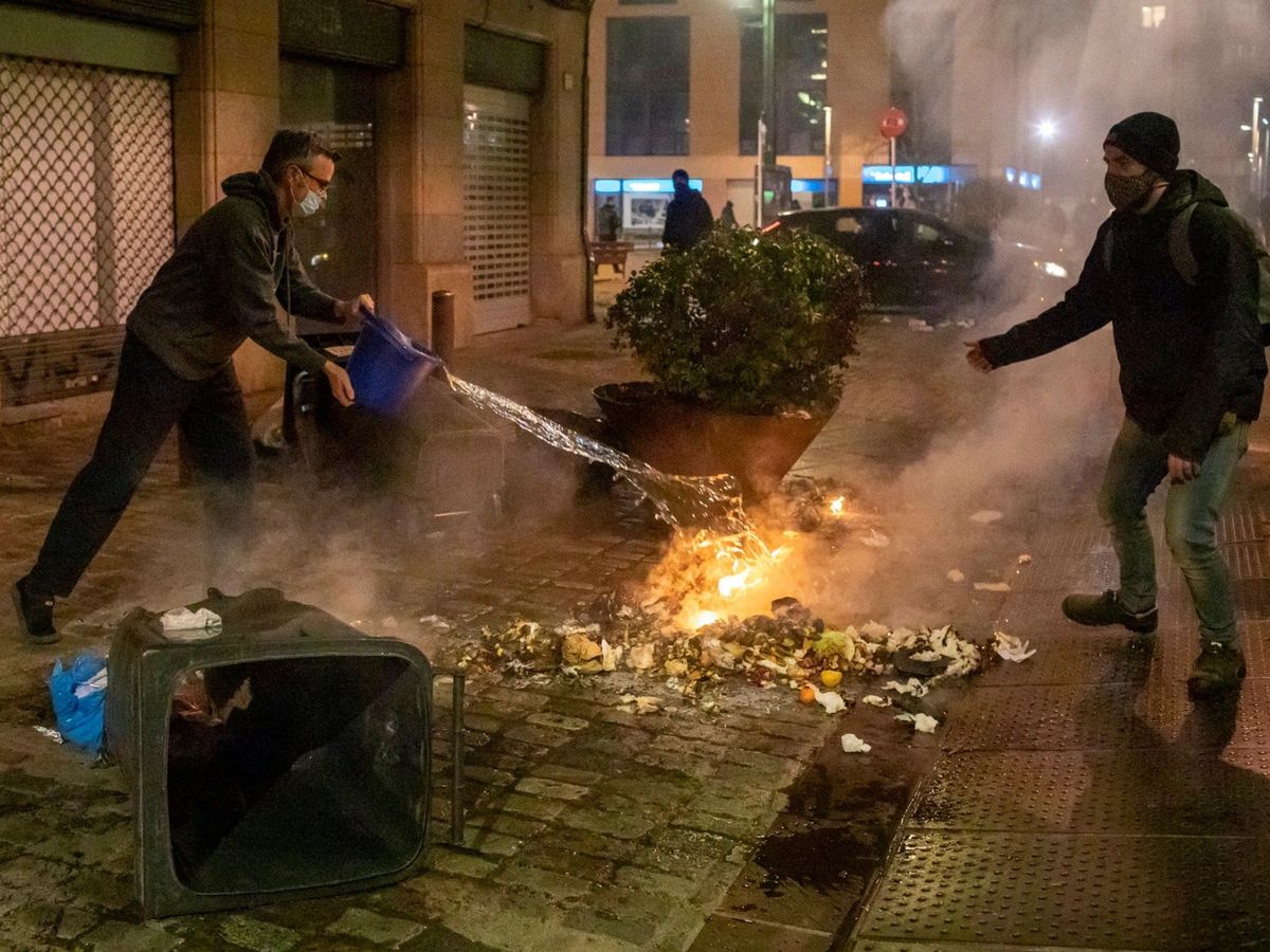 Foto: Unos vecinos apagan un fuego provocado por los manifestantes en Girona. (EFE)