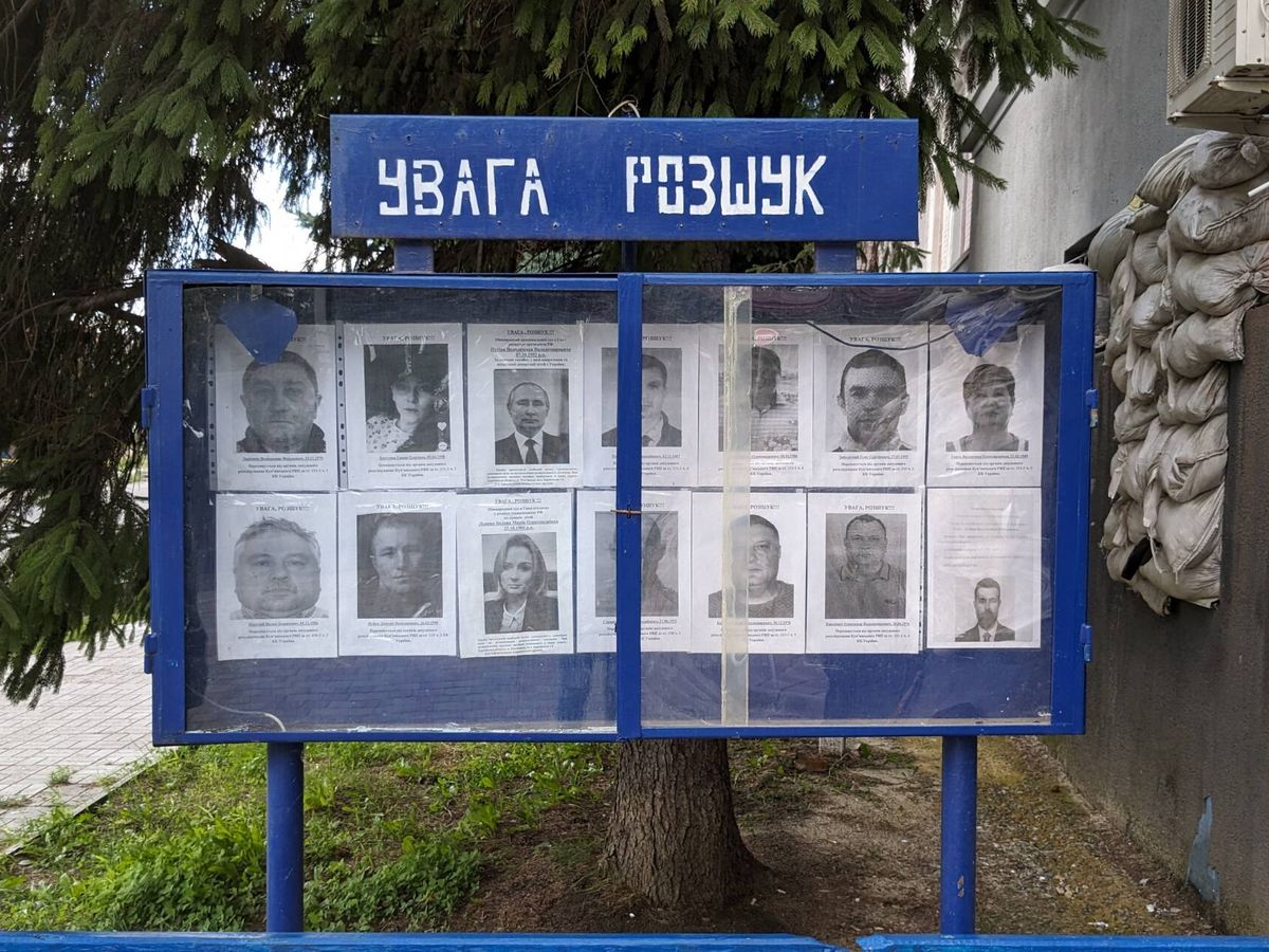 Foto: El tablón de "Más buscados" en Kupiansk. Además de criminales o colaboracionistas locales, entre las caras están Vladímir Putin y Maria Alekseyevna Lvova-Belova, Comisionada rusa para los Derechos del Niño. (Alicia Alamillos)
