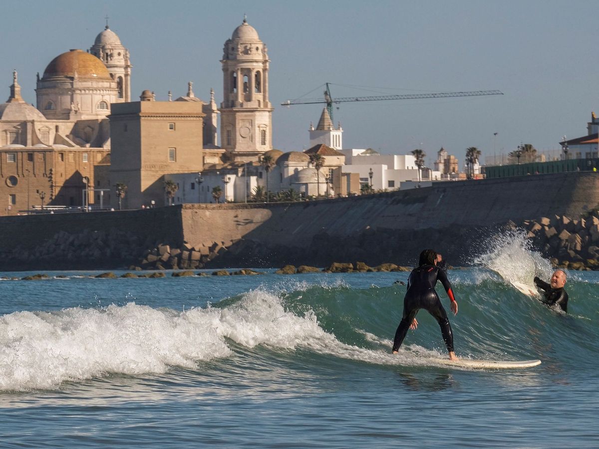 Foto: Dos personas practican surf en la playa de Santa María del Mar de Cádiz. (EFE/Román Ríos)