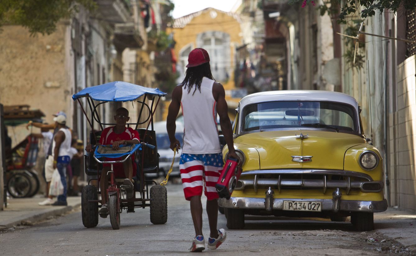 Un hombre camina cerca a una vehículo clásico y un bicitaxi en La Habana, el 26 de diciembre de 2017. (Reuters)